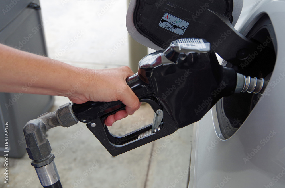 Hand holding Gas pump inserted into gas tank of a car Hand holding Gas pump inserted into gas tank of a car
