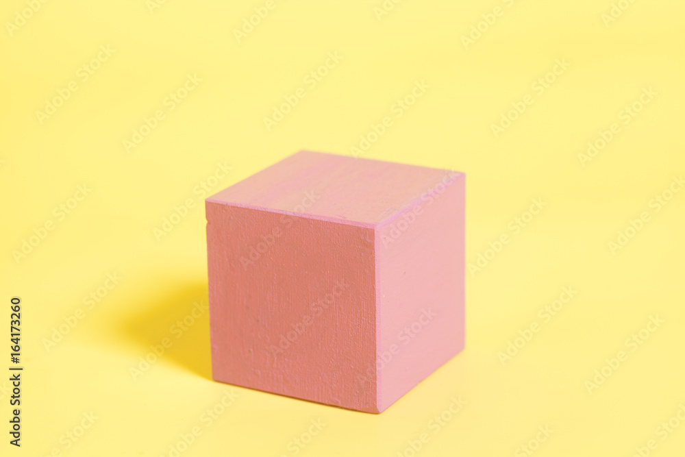 Red wooden cube on yellow background Red wooden cube on yellow background