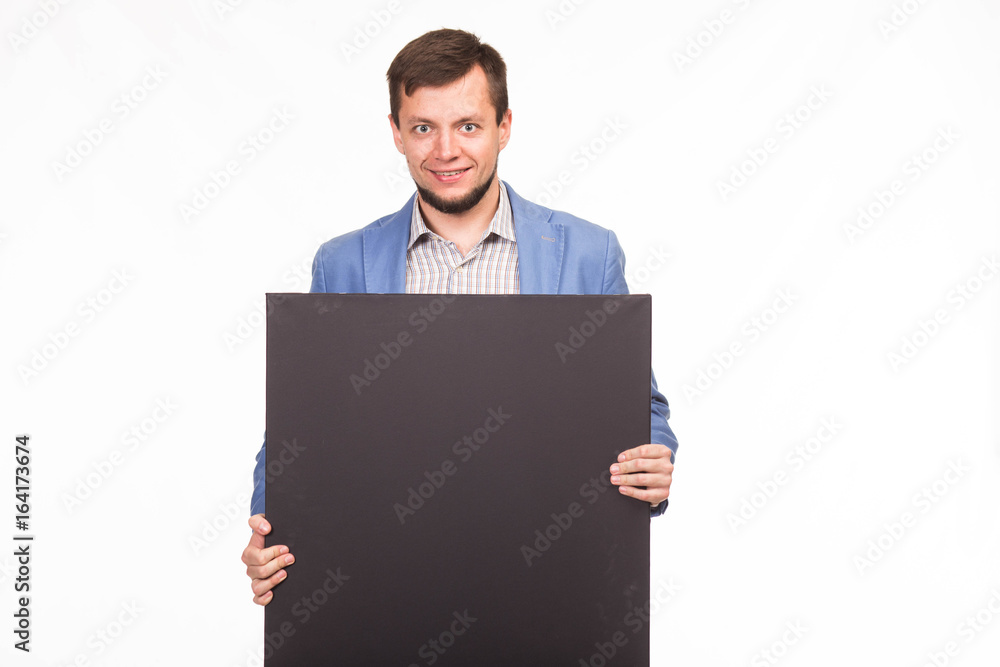 Young happy man portrait of a confident businessman showing presentation, pointing paper placard gray background. Ideal for banners, registration forms, presentation, landings, presenting concept. Young happy man portrait of a confident businessman showing presentation, pointing paper placard gray background. Ideal for banners, registration forms, presentation, landings, presenting concept.