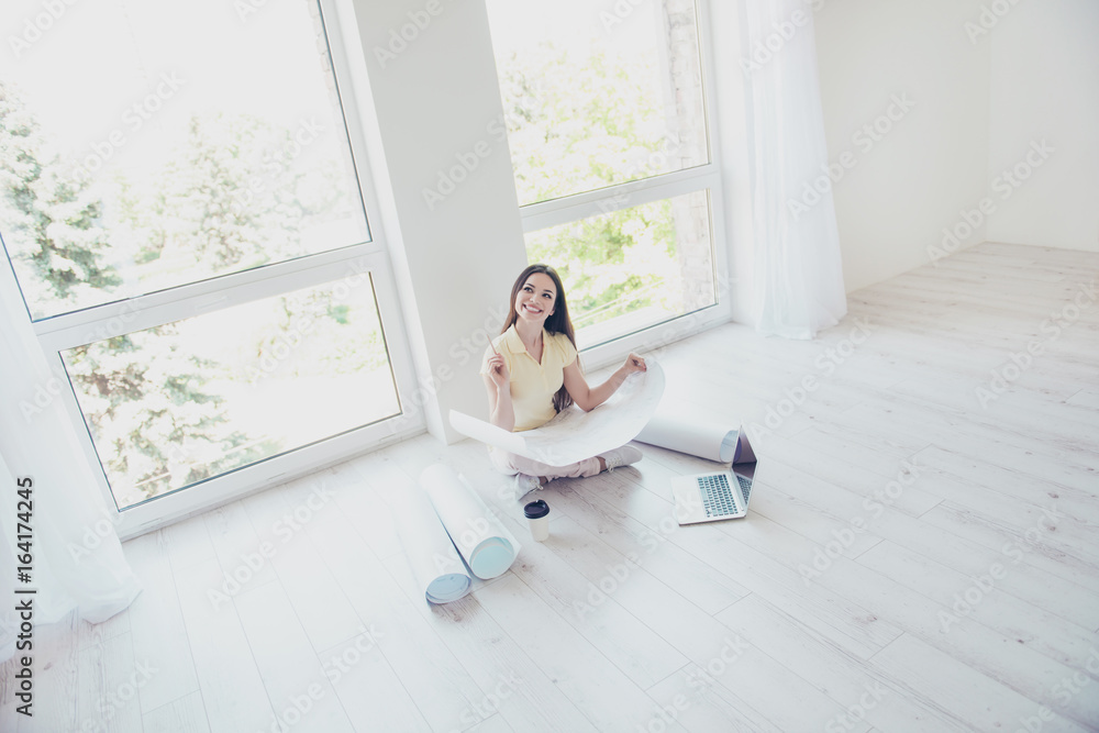 Topview of lady designer dreaming and creating the new project, sitting at the floor, looking away, smiling, in casual wear, with crossed legs Topview of lady designer dreaming and creating the new project, sitting at the floor, looking away, smiling, in casual wear, with crossed legs