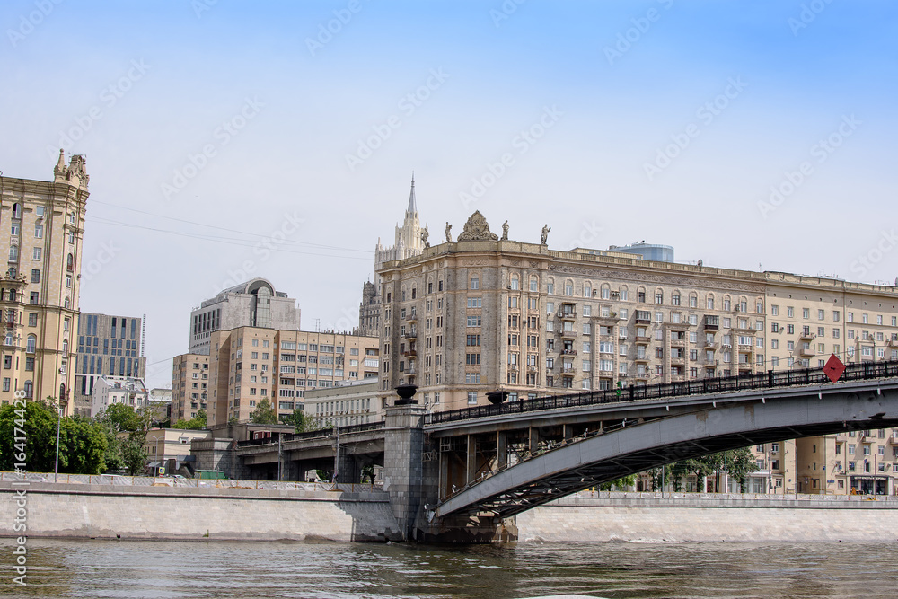 Metal bridge across the river to the city, embankment with houses