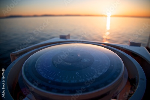 Navigation in the sea. Compass and sunrise at the horizon.