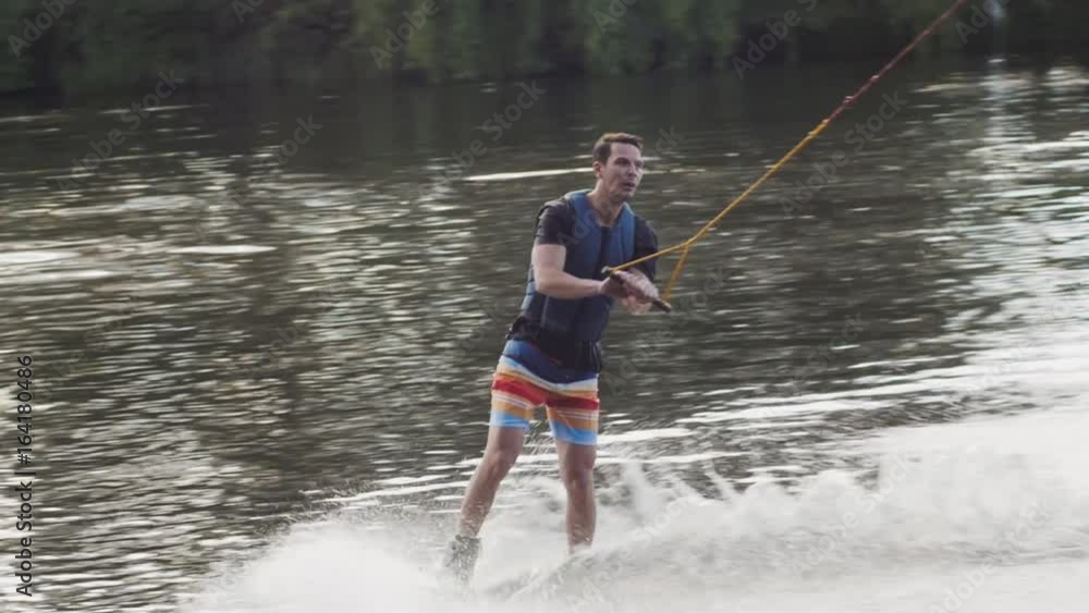Wakeboarder ride on cable wakeboard in park, outdoor extreme slow motion on water, surfing athlete on water Wakeboarder ride on cable wakeboard in park, outdoor extreme slow motion on water, surfing athlete on water