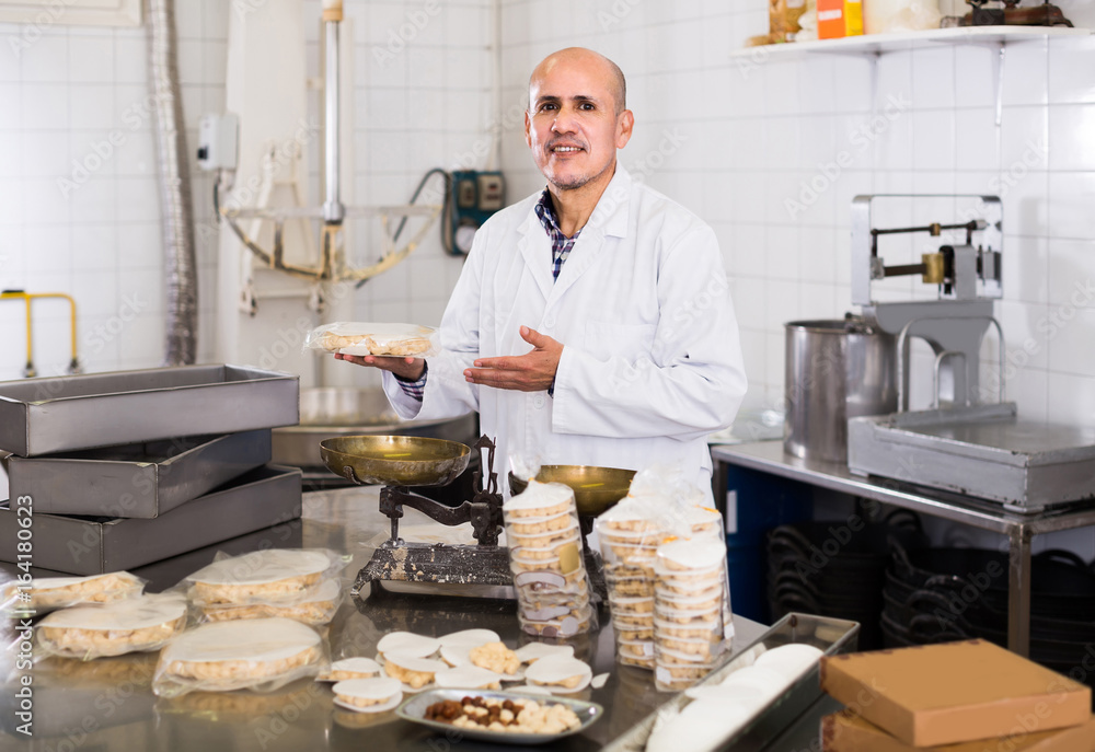 Portrait of  mature male with packing of turron in food factory