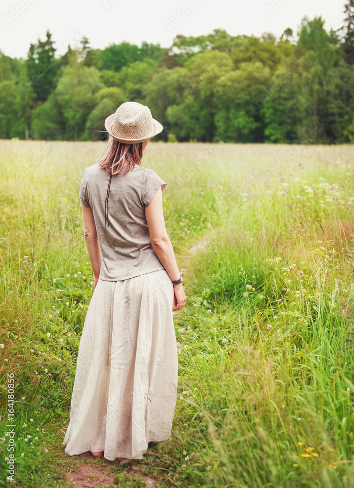 Beautiful woman in long dress on the summer meadow