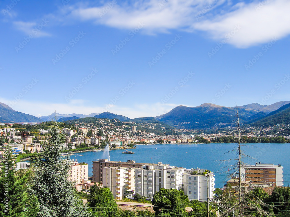 Aerial view of Lugano city with houses, lake and cityscape, and alpine Swiss mountains in Switzerland