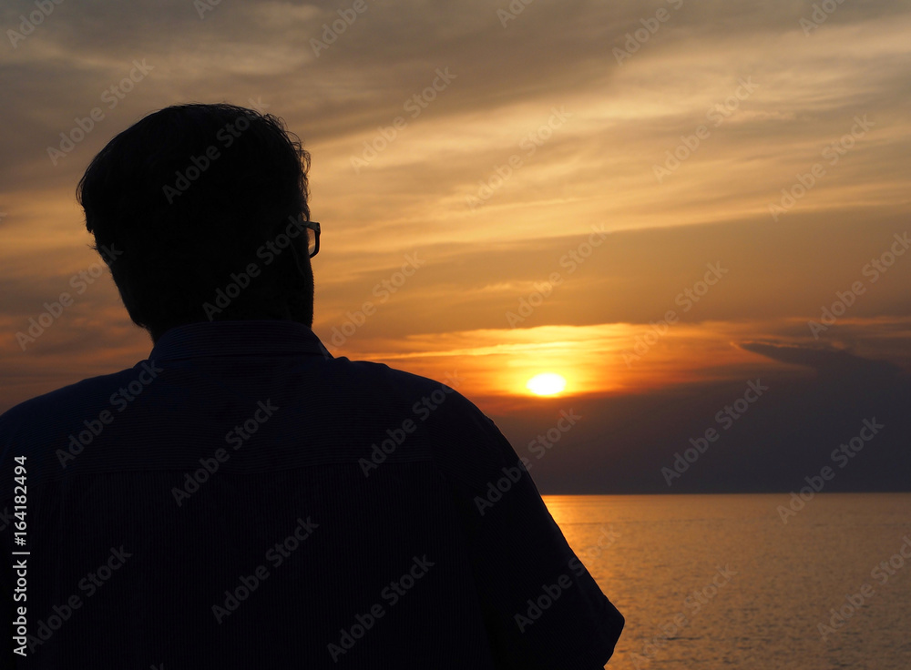Silhouette of senior man with glasses watching on sunset.