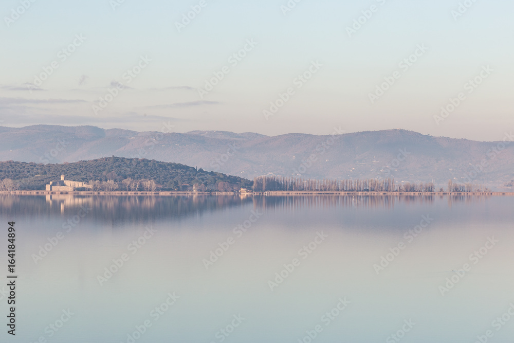 Isola Polvese (Trasimeno Lake, Umbria) perfectly reflecting on water, with warm sunset colors