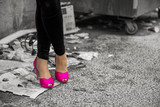 Woman in pink shoes standing in alley by garbage