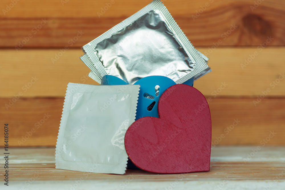 condoms and red love heart, flower on wooden background. space for text