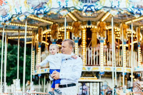 Father and son playing in amusement park at the evening time. Concept of friendly family