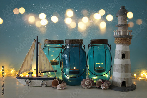 Fotografie Magical mason jars whith candle light and wooden boat on the shelf