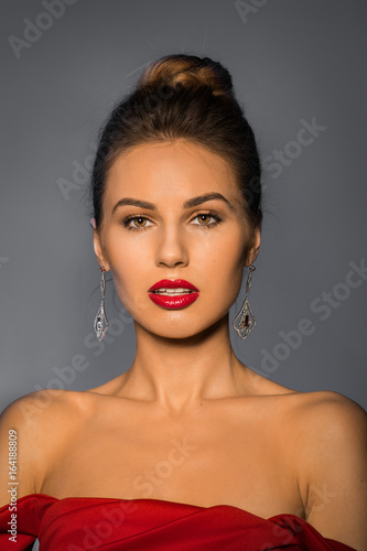 smiling woman portrait. girl wearing red dress. grey background.