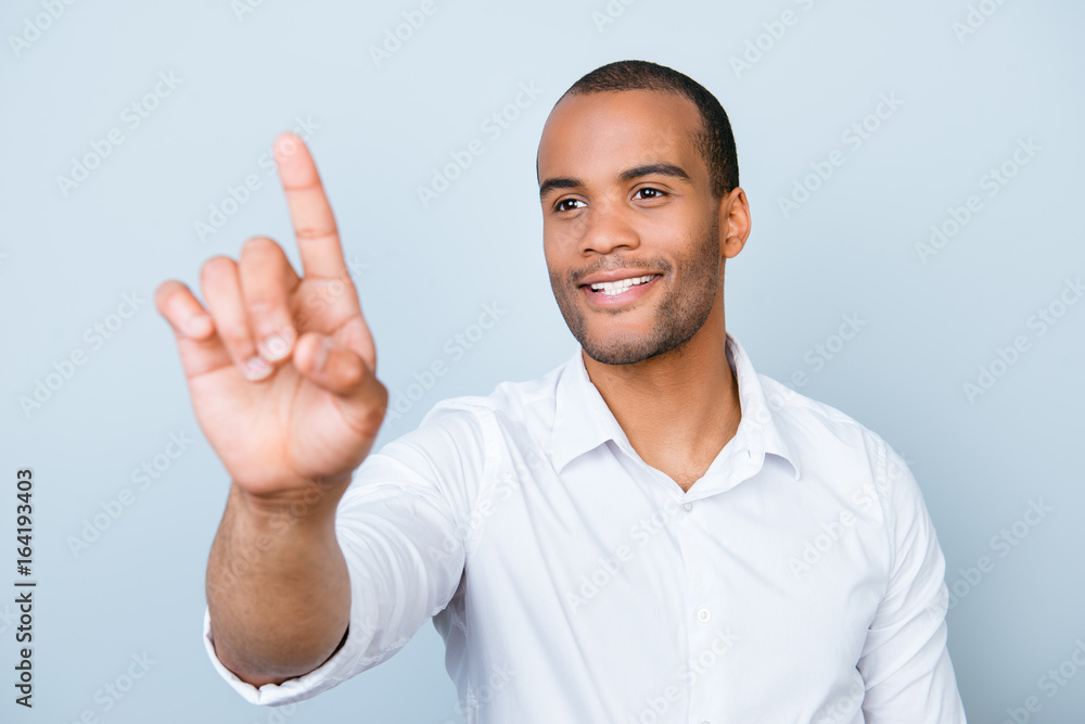 Fototapeta premium Portrait of smiling successful american entrepreneur touching virtual screen, standing on pure background, in white formal wear