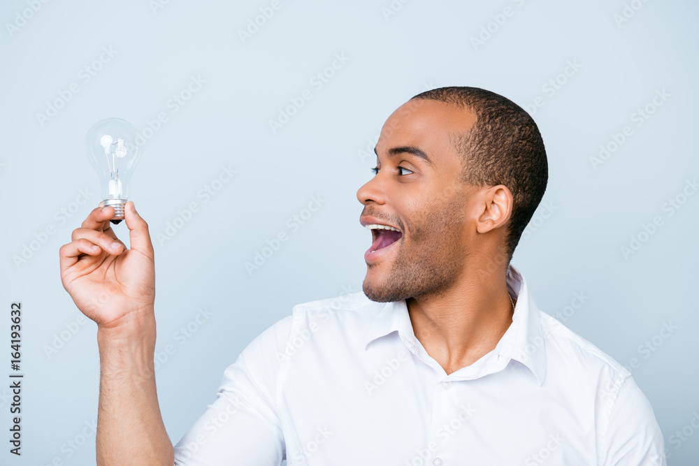 Eureka! Have an idea! Success concept. Young african student is standing with a lamp in his hand on pure background and formal white outfit Eureka! Have an idea! Success concept. Young african student is standing with a lamp in his hand on pure background and formal white outfit