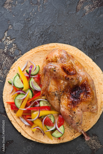 Tortillas with baked halved chicken and vegetable salad, flat-lay on a brown stone surface with space