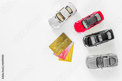 Choosing car concept. Toy cars and bank card on white background top view copyspace