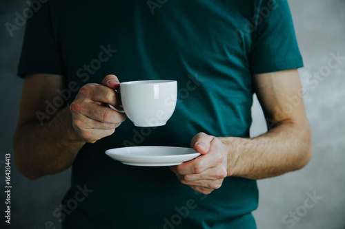 Male hands holding white coffee cup.Mock up of clean coffee cup.Horizontal mockup, shurt background photo