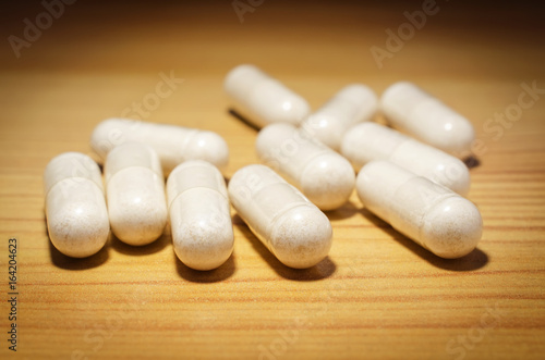 Herb capsule medicine on the wooden surface. Closeup