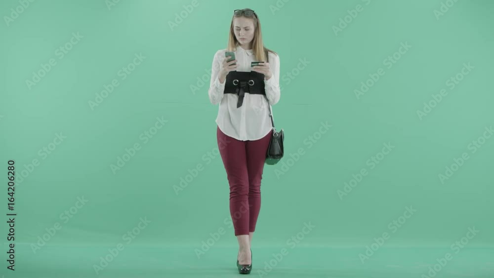 a girl stands with a card and a phone in hands a girl stands with a card and a phone in hands