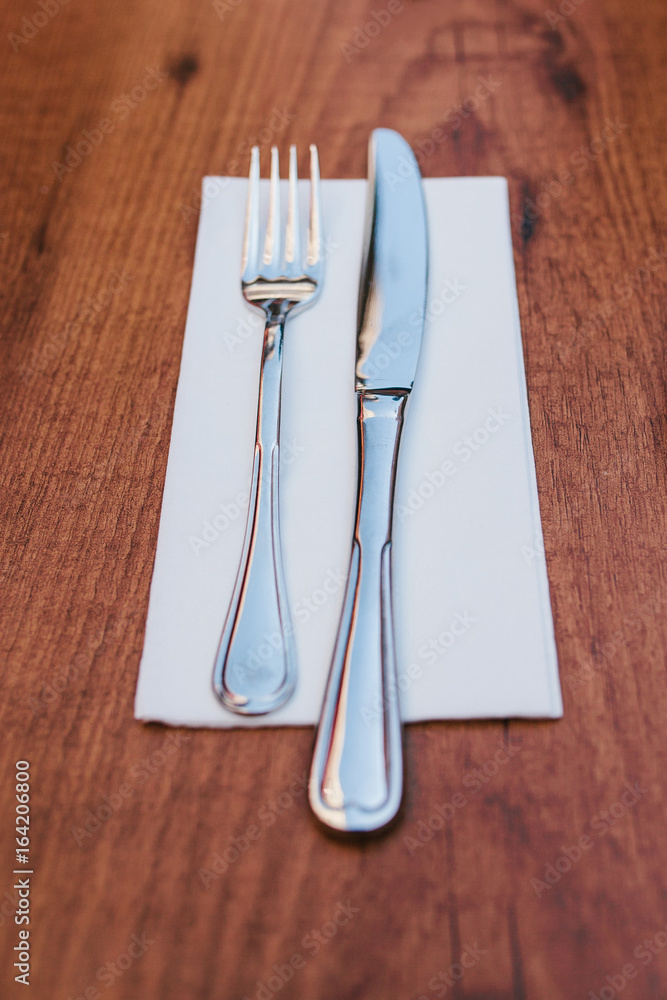 Knife and fork at napkin on wooden background. Table setting Knife and fork at napkin on wooden background. Table setting