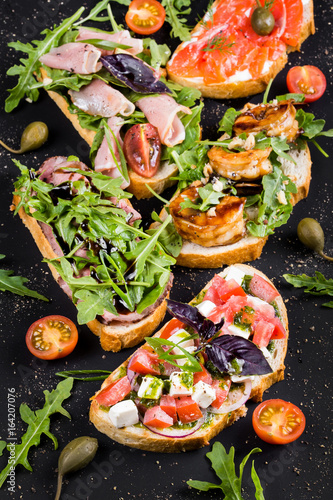 Brushetta set for wine. Variety of small sandwiches with prosciutto, tomatoes, parmesan cheese, fresh basil