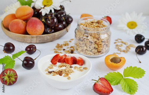 Healthy Fresh Breakfast Yogurt with Granola Fruits Berries Strawberries Apricot Melon Cherry Chamomile Close up White Background