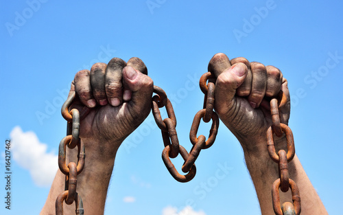 Tableau sur toile Two male hands holding a rusty metal chain