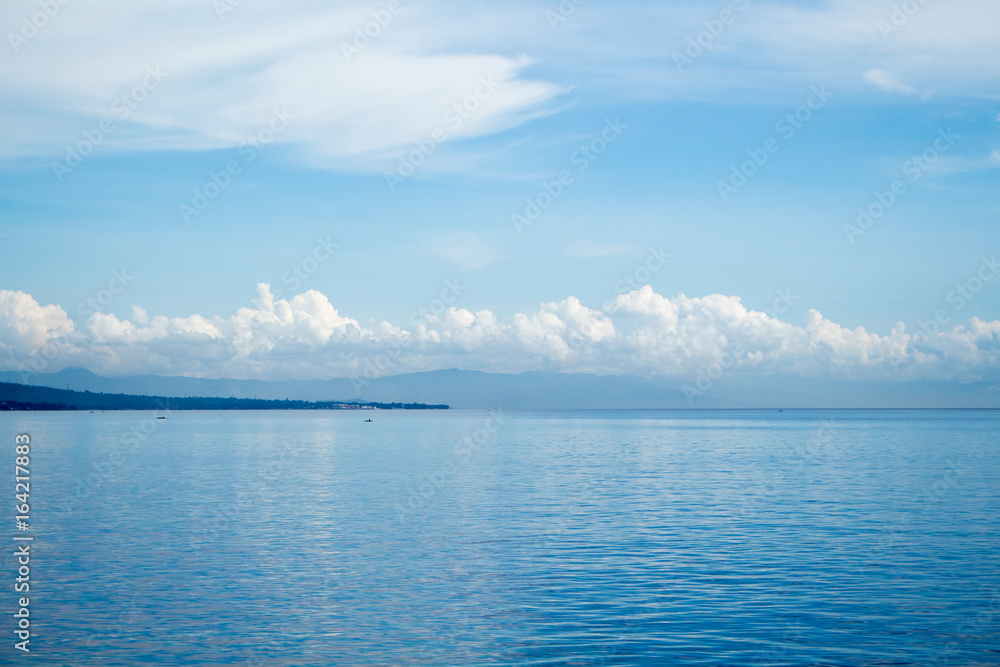 Tropical seascape with distant island and blue sky. Relaxing sea view with still seawater. Tropical seascape with distant island and blue sky. Relaxing sea view with still seawater.