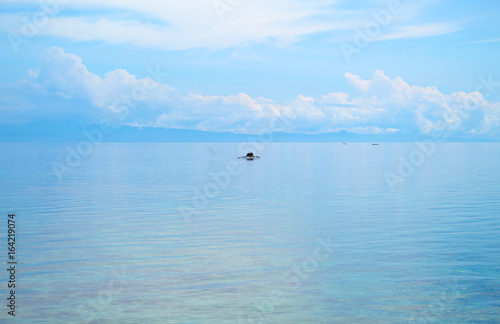 Seascape with fisherman boat and blue sky. Relaxing sea view with still seawater.