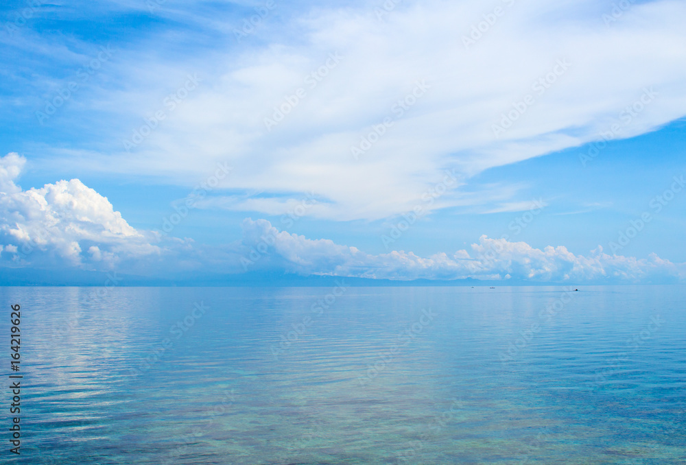 Aquatic seascape with distant island and blue sky. Relaxing sea view with still seawater.