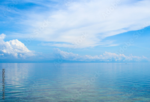 Aquatic seascape with distant island and blue sky. Relaxing sea view with still seawater.