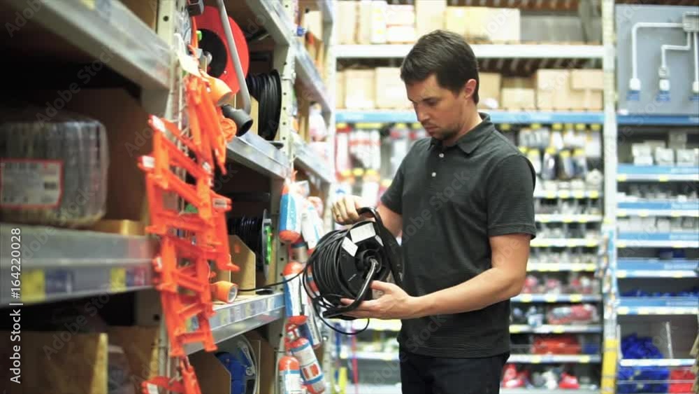 Man in the mall choosing an electric wire extension cord with a long cable. Man in the mall choosing an electric wire extension cord with a long cable.