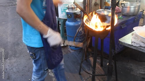 Chef preparing food with stir fry. Street food at Yaowaraj road in Bangkok. photo