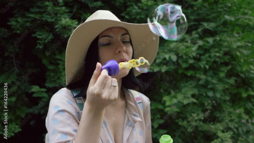Slow motion of smiles young beautiful happy woman in hat blowing bubble in the park Slow motion of smiles young beautiful happy woman in hat blowing bubble in the park