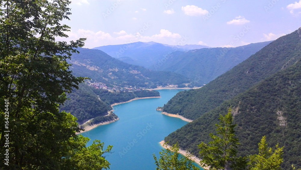 Amazing landscape with blue lake, high mountains, green trees and clear sky. Aerial top view on the river Piva, Montenegro