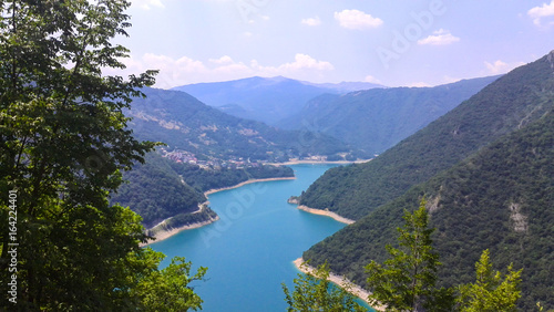 Amazing landscape with blue lake, high mountains, green trees and clear sky. Aerial top view on the river Piva, Montenegro © Alexander N.