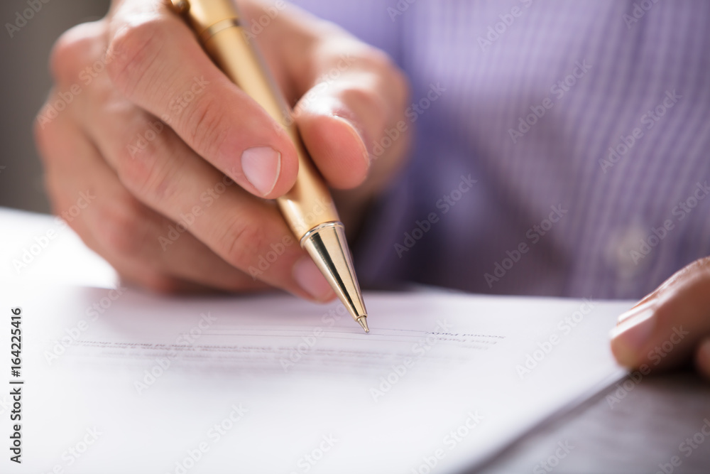 Businessperson's Hand Signing Document With Pen Businessperson's Hand Signing Document With Pen