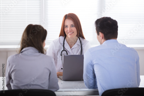 Couple Sitting In Front Of Female Doctor