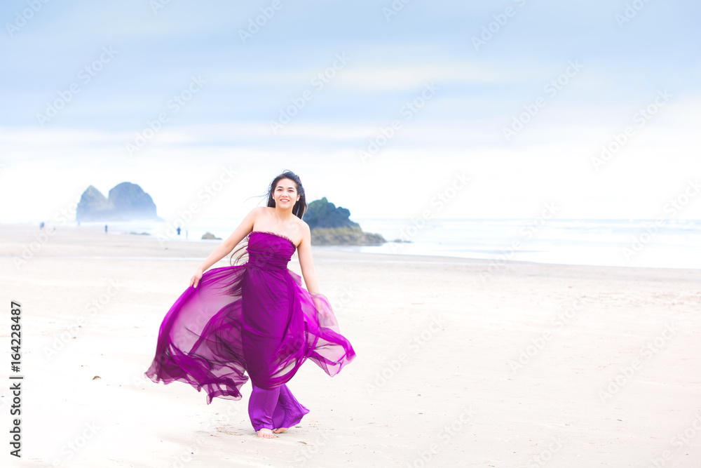 Young woman in flowing magenta dress standing on beach Young woman in flowing magenta dress standing on beach