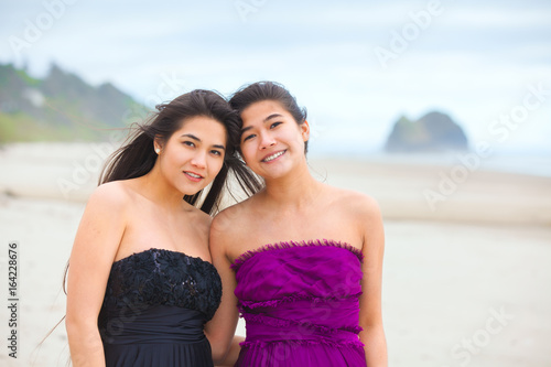 Two teen girls in elegant dresses smiling together on beach © Jaren Wicklund