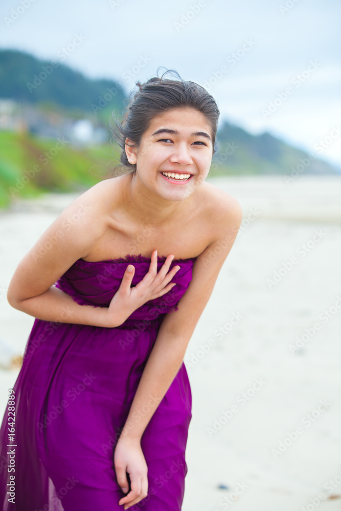 Happy, smiling teen girl in purple dress laughing on beach Happy, smiling teen girl in purple dress laughing on beach
