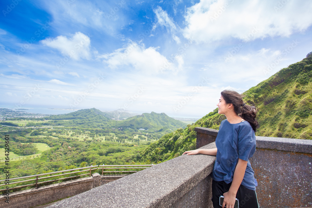 Teen girl standing looking out over view of eastern Oahu