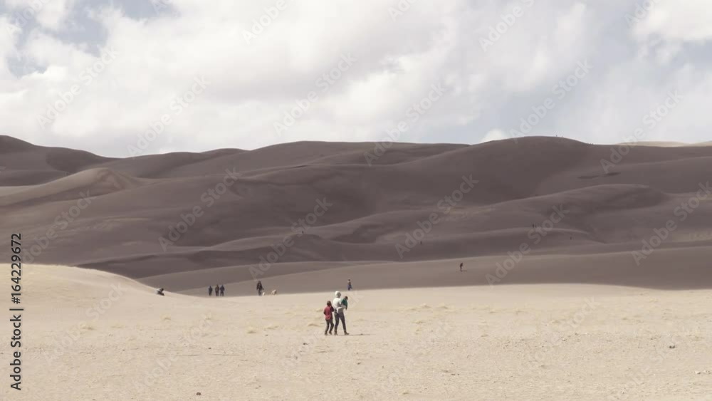 Great Sand Dunes National Park, Colorado, USA: View of tourists climbing the desert sand dunes on a windy day Great Sand Dunes National Park, Colorado, USA: View of tourists climbing the desert sand dunes on a windy day