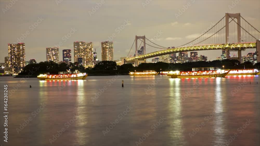 Lighted boats on Tokyo Bay with Tokyo skyline and Rainbow Bridge, time lapse, Japan