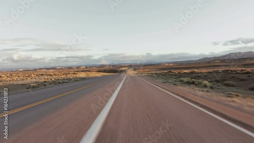 Driving USA: Beautiful point of view shot driving on long straight road in desert grasslands at sunrise/sunset, Wyoming