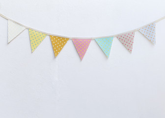 Design vintage fabric party flag over white cement wall texture background, outdoor day light