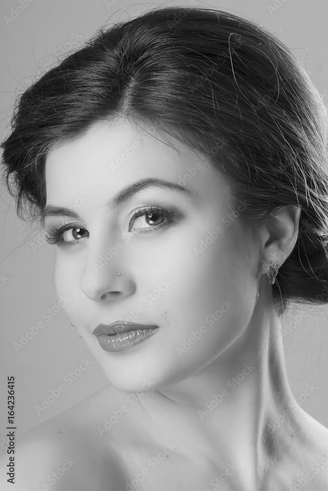 Naklejka premium Close-up portrait of brown-haired girls with clean skin. Isolated grey background. A playful look. Black and white image.