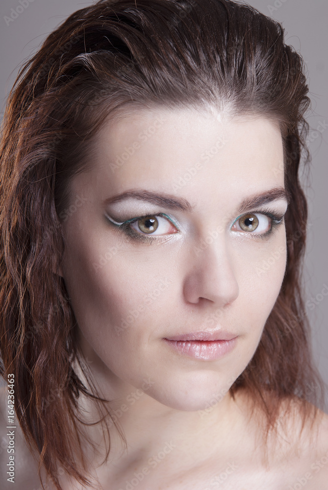 The brown-haired girl with bright makeup and clean skin. Close-up portrait. Isolated grey background. Hairstyle graduated bob. The brown-haired girl with bright makeup and clean skin. Close-up portrait. Isolated grey background. Hairstyle graduated bob.
