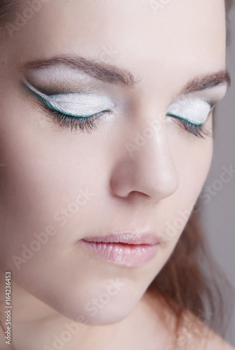 Close-up portrait of girl with clean skin and bright makeup. Demonstration of makeup cat eyes.